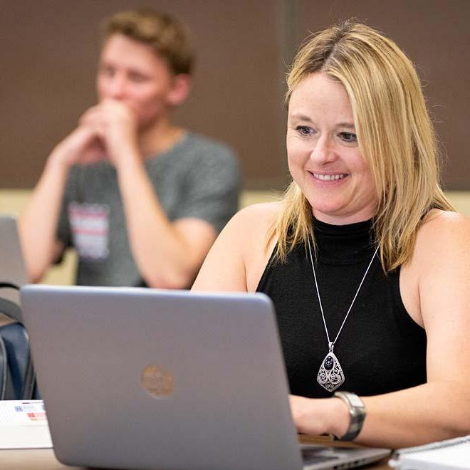 Smiling adult student in evening class on laptop